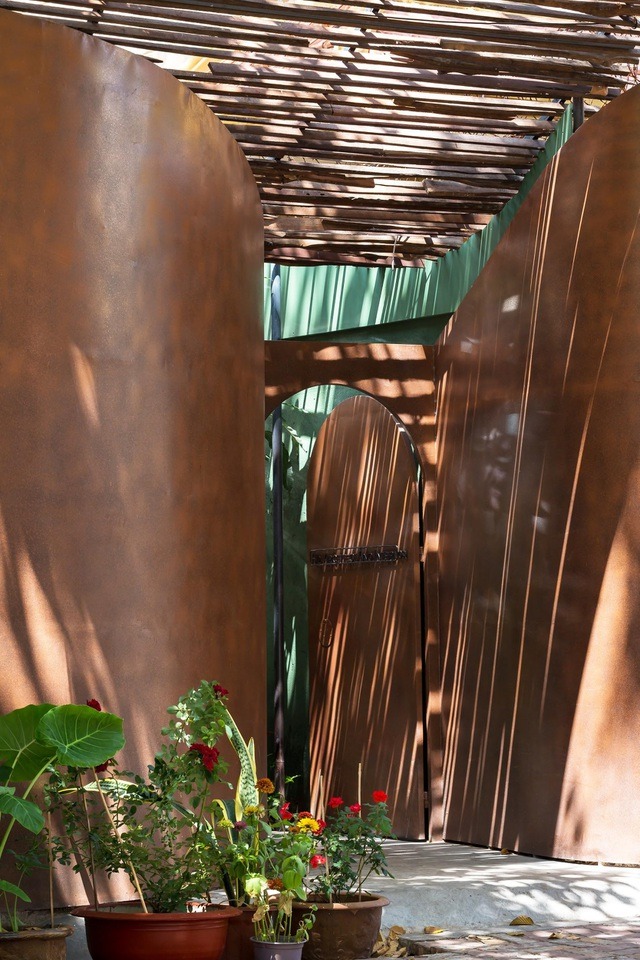 Ngay đằng sau cánh cửa là một khoảng sân vườn xanh mát mắt. Khoảng vườn trở thành không gian đệm trước khi tiến vào khu vực chức năng chính.